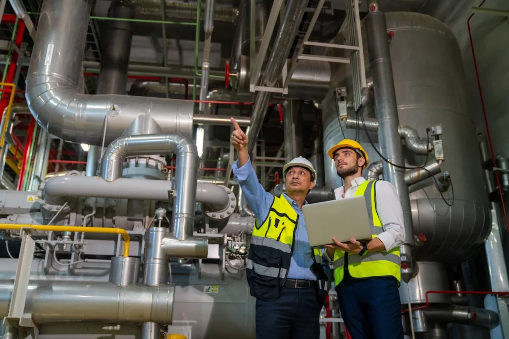 deux hommes qui discutent dans une usine avec un ordinateur dans les bras