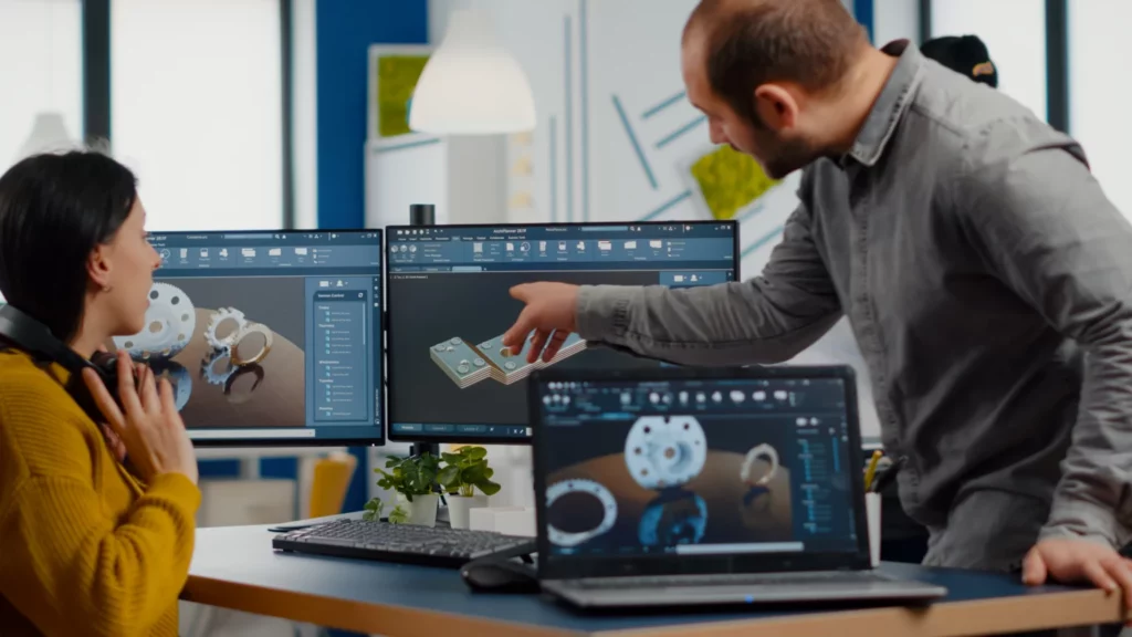 deux collaborateurs qui echangent devant un ordinateurs qui montre des plans 3D