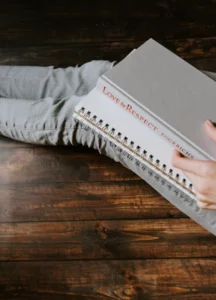 personne assise par terre avec livre sur les jambes