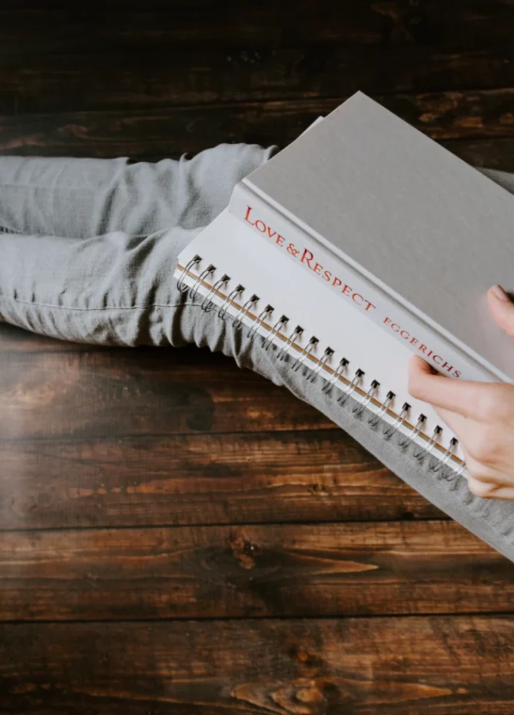 personne assise par terre avec livre sur les jambes