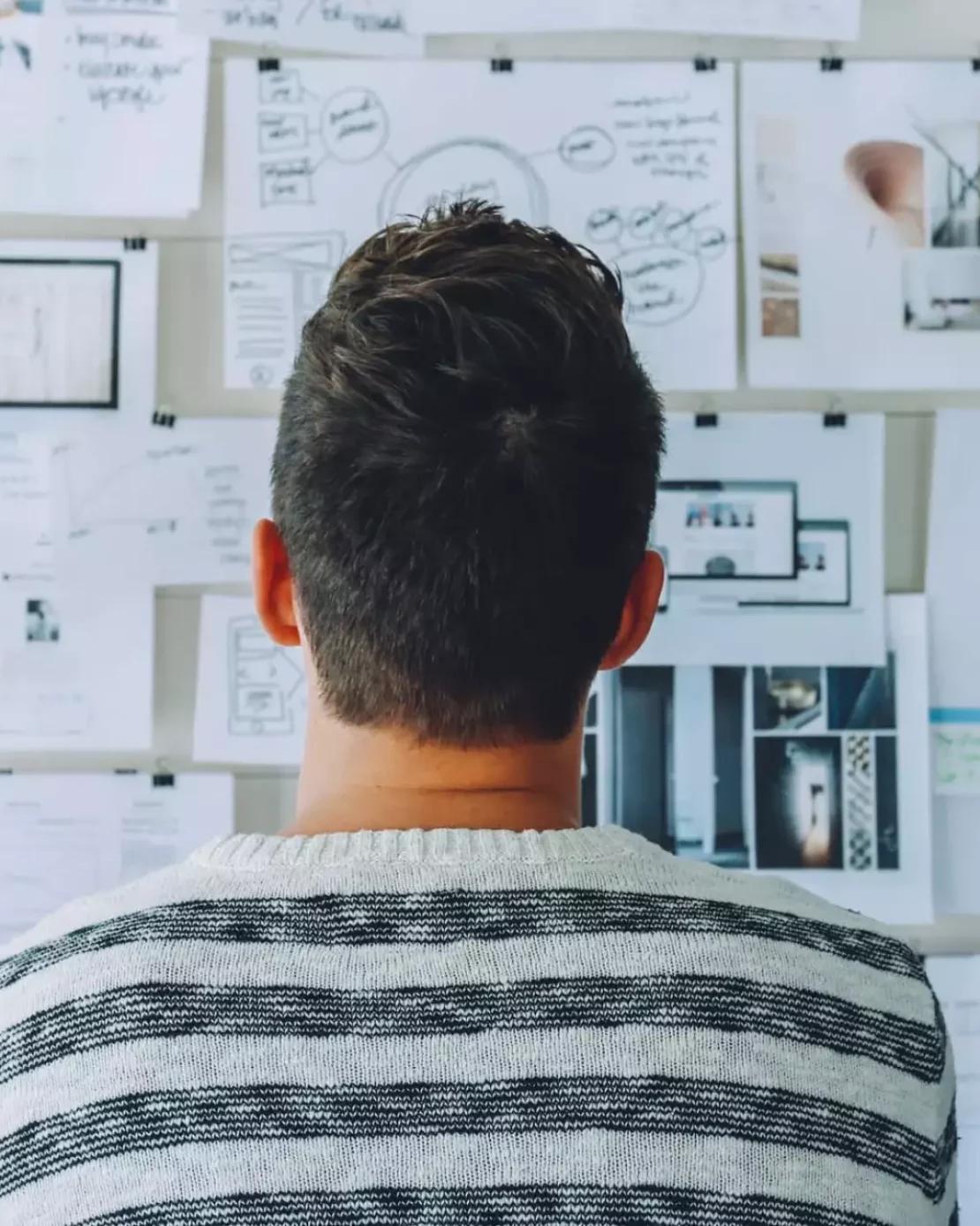 un homme regardant un mur couvert de papier, en reflexion
